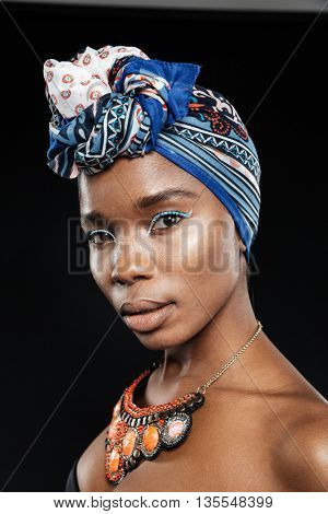 Close-up portrait of a beautiful african woman in shawl on head isolated on the black background