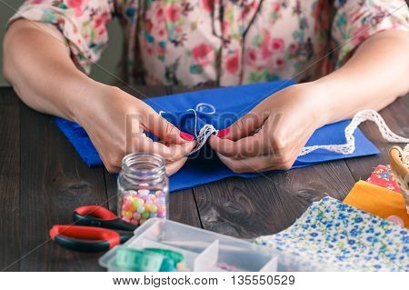 Close-up of woman's hand stitching quilting on dark rustic Wood Background