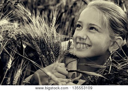 portrait of a little girl on the field with spikelets