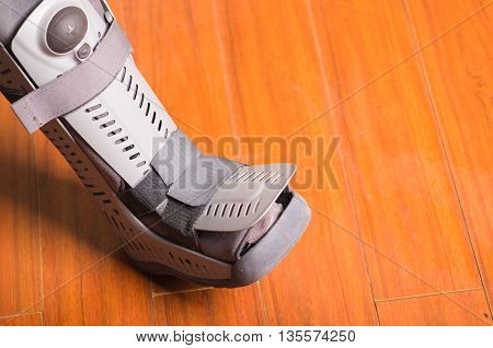 Orthopedic gray boot, when some part of the feet is affected, wooden background floor.