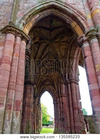 The ruins of pink colored Melrose Abbey in the Scottisch Borders region in Scotland