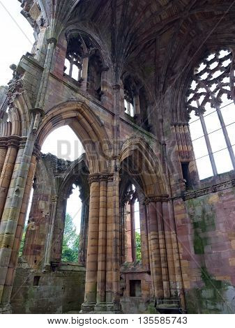 The ruins of pink colored Melrose Abbey in the Scottisch Borders region in Scotland