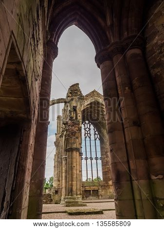 The ruins of pink colored Melrose Abbey in the Scottisch Borders region in Scotland