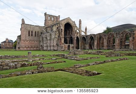 The ruins of pink colored Melrose Abbey in the Scottisch Borders region in Scotland