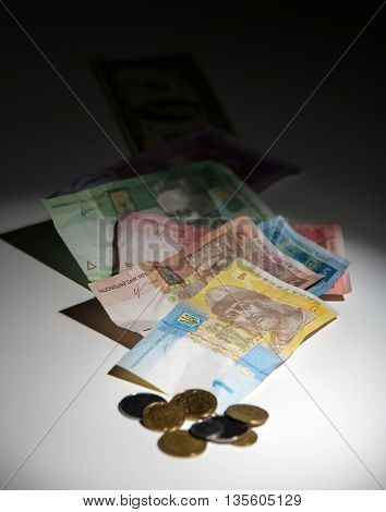 Ukrainian hryvnia and pennies on a white background with gradient to black. Hryvnia to focus on a light background is out of focus dollars on the black.