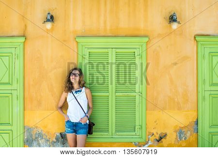 Young blond woman in typical Greek town with colorful buildings on Kastelorizo Island, Greece, Europe