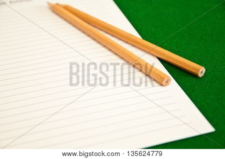 two wood pencil and paper in blackground green