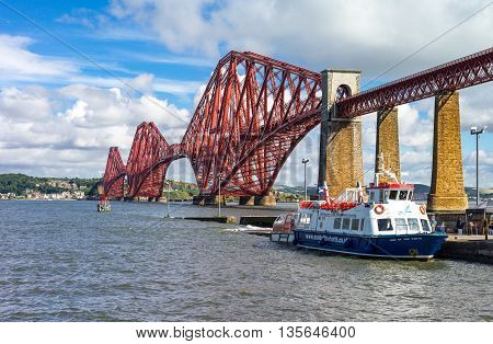 South Queenferry Scotland - July 29 2012: Lothian area the Forth Rail Bridge with a tour boat moored