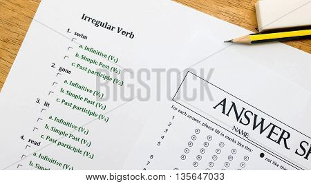 english exercise, pencil and answer sheet on brown wooden table represent testing english grammar
