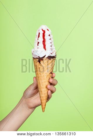 Ice cream in hand. Child's hand holding ice cream close-up on a light green background. stock photo