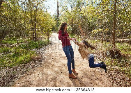 Mother and daughter being spun in circles at park having fun
