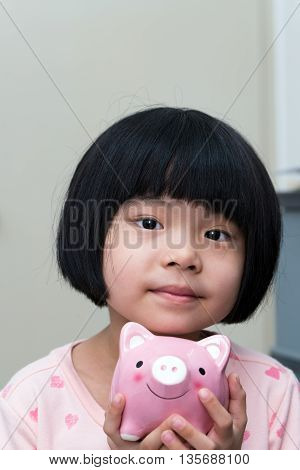 Asian Child With Piggy Bank