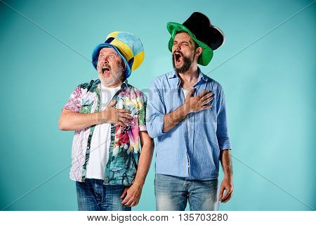 The two football fans singing the national anthem over blue background