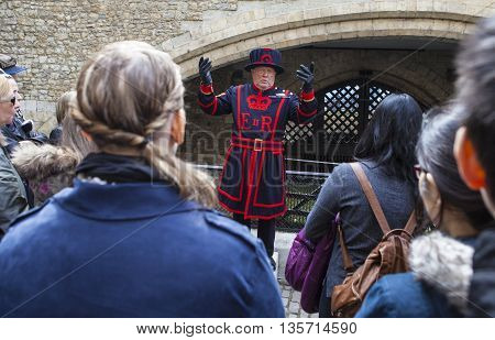 LONDON UK - APRIL 10TH 2016: A Yeomen Warder talking to visitors during a tour of the historic Tower of London on 10th April 2016.