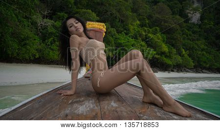 Beautiful young Asian woman in a crochet swimsuit posing on the boat
