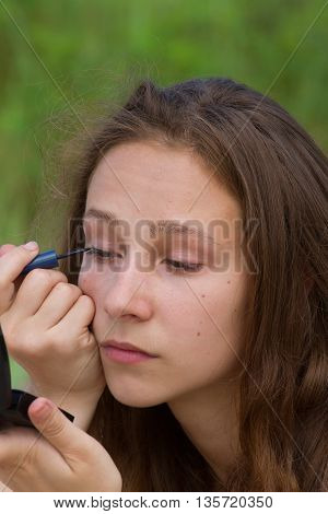 Blonde girl doing make-up, closeup photo. Eyeliner