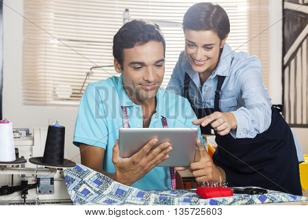 Tailors Discussing Over Digital Tablet At Workbench