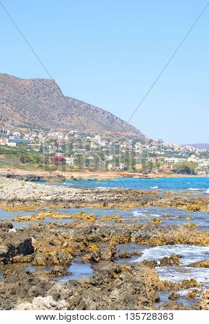Rocks on the shore of the sea and the city of Hersonissos Crete Greece.
