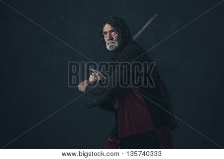 Senior knight in hauberk attacking with sword.