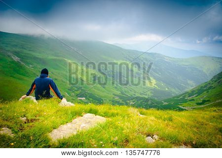Beautiful mountains landscape with lake and clouds in Carpathian mountains and man looks