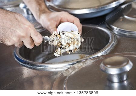 Hands Filling Butterscotch Ice Cream With Spatula In Cup