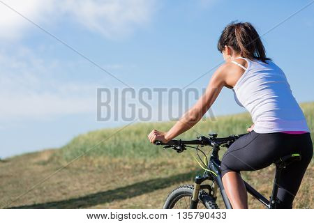 Sport bike woman on a meadow with a beautiful landscape. Healthy lifestyle