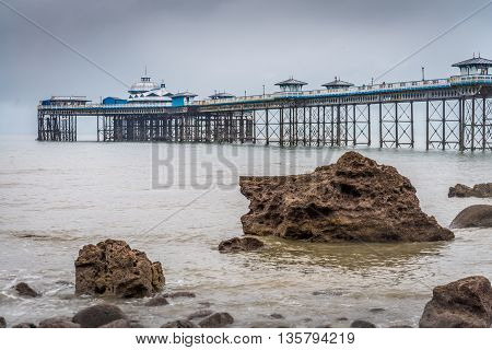 Llandudno Pier receding into the distance above rocky outcrops on the beach
