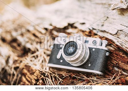 35mm Vintage Old Retro Small-Format Rangefinder Camera On Old Fallen Wood Tree In Forest.