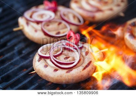 cumberland sausage, spiral pork sausage on bbq grill with flame, homemade