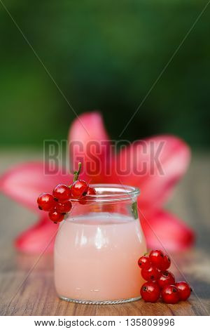 jar of cold pink cocktail on green background bokeh
