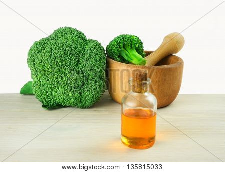 Fresh Broccoli in wooden mortar and seed oil in vintage bottle