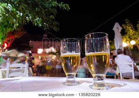 Two glasses of beer on a table.