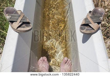 Man feet refreshing in a cool irrigation canal during the hottest day hours Vegas Altas del Guadiana Spain