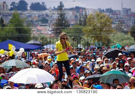 QUITO, ECUADOR - JULY 7, 2015: Just for a photo a woman is satnding up on a men shoulders, mobile phone camera on her hands.