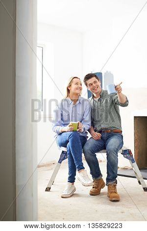 Young Couple Sitting In Property Being Renovated