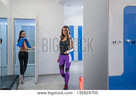 Charming girls pose in locker room of sports center