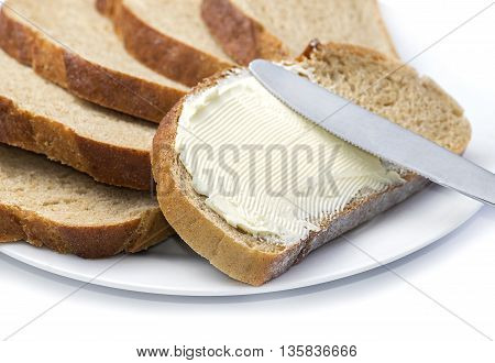 Close up a knife spreading butter on bread.