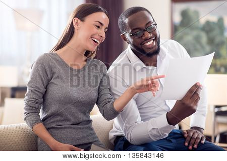 Thats interesting. Pretty young woman pointing on the paper which her afro American colleague holding in his hand