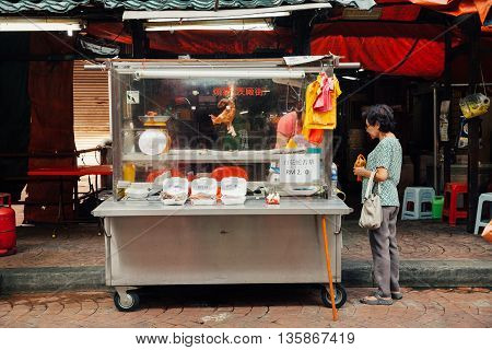 KUALA LUMPUR MALAYSIA - MARCH 17: Woman buying meat at the street stall in Chinatown Kuala Lumpur Malaysia on March 17 2016.
