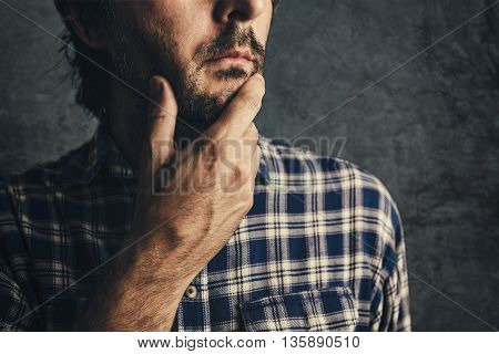Casual man in plaid shirt thinking and contemplating low key selective focus portrait