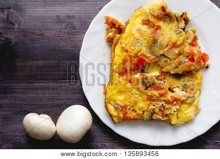 a piece of omelet on a white plate and two mushroom. Top view. Blank space