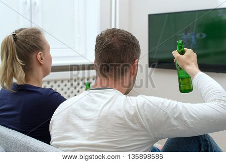 young couple watching American football on tv.