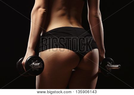 Sexy fitness ass close-up. Part of fitness body on a black background. Perfect female sports figure. Fitness woman posing in the studio. Fitness photo shoot in the studio. Fitness bikini