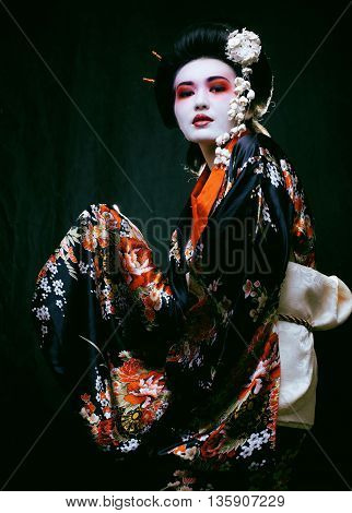 Young beautiful asian woman's portrait, geisha in kimono on black