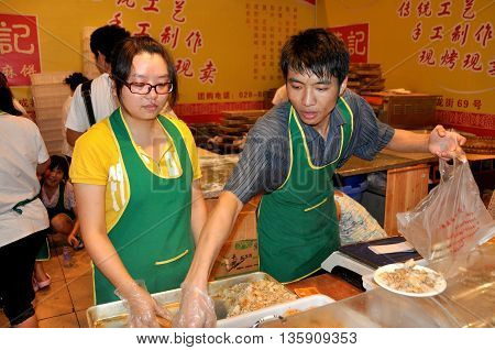 Chengdu China - September 15 2010: Two workers selling food at the 10th Chinese Moon Cake Festival at the annual Sichuan and Tianfu Food Fair