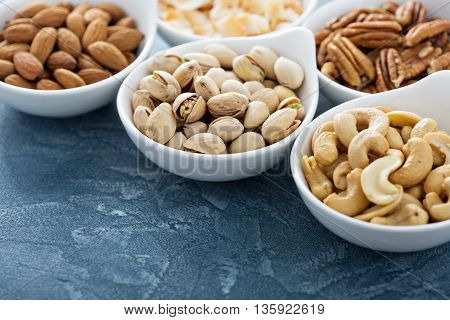 Variety of nuts in small white bowls healthy snacks