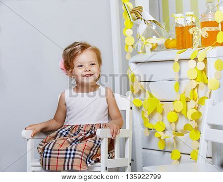 Beautiful little girl.Blue-eyed blonde.White chair.Lemonade.Children's room. Happy small girl portrait.