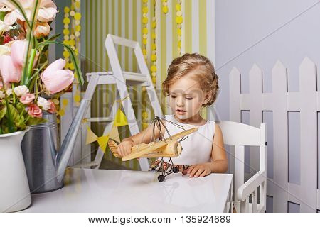 Beautiful little girl playing toys.Blue-eyed blonde.White chair.Children's room. Happy small girl portrait.