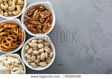 Variety of healthy snacks in white bowls pretzels and nuts