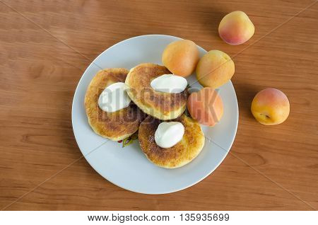 Grandma's curd pancakes with their hands with scented sour cream and sweet apricots
